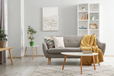 Gri kanepe, masa ve raf ünitesiyle aydınlık oturma odasının içinde.