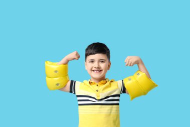 Mavi arka planda şişme kolluklu şirin bir çocuk.