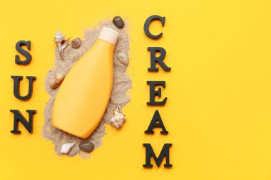 Güneş kremi, bir şişe güneş kremi ve sarı arka planda deniz kabukları.