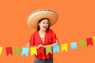 Meksika şapkalı ve turuncu arka planda çelengi olan mutlu genç kadın.