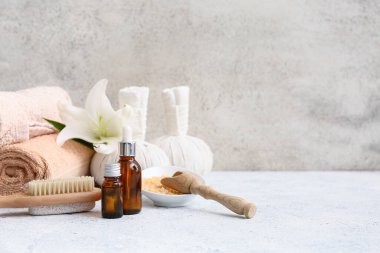 Havlular, bitkisel poşetler, serum şişeleri ve grunge arkaplanda bir kase deniz tuzu olan güzel bir spa kompozisyonu.