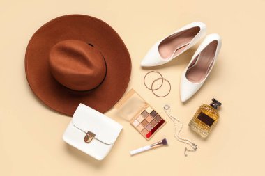 Bir şişe parfüm, göz falı, bej arka planda çanta ve aksesuarlar.