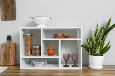 Wooden kitchen counters with houseplant and shelves near white wall