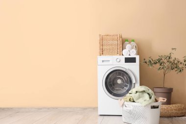 Çamaşır sepetli ve çamaşır makineli çamaşır odasının içi.