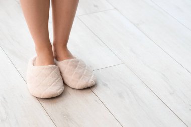 Evdeki lamine zeminde yumuşak terlikli bir kadın, yakın plan.