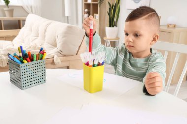 Evdeki masada keçeli kalemle çizen komik küçük çocuk.