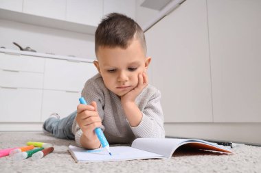 Mutfakta yere keçeli kalem çizen komik çocuk.