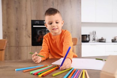Mutfaktaki masasında keçeli kalemlerle çizen sevimli küçük çocuk.