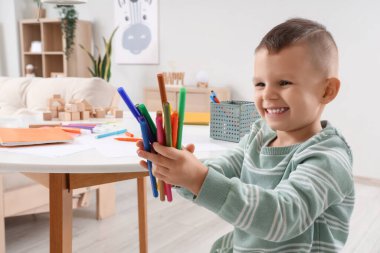 Evde keçeli kalemleri olan sevimli küçük bir çocuk.