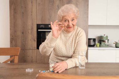 Mutfakta haplarla gülümseyen yaşlı kadın.