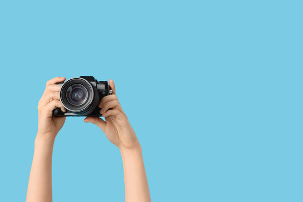 Женские руки с современной камерой на синем фоне