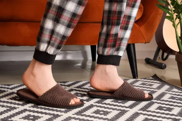 Evde terlik giymiş erkek bacakları. Yakın çekim.