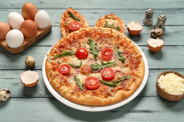 Tavşan kulaklı Paskalya pizzası, gri ahşap arka planda yumurta ve peynir.