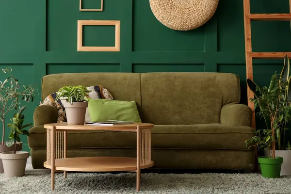 Yeşil kanepesi, ahşap masası ve bitkileri olan şık bir oturma odası.
