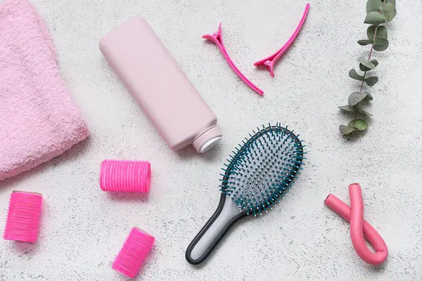 Saç fırçası, saç tokaları ve beyaz grunge arka planda bir şişe şampuan.