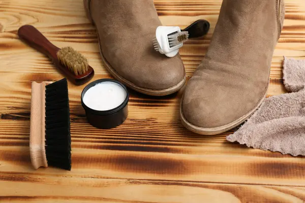 Ahşap arka planda çizmeler, fırçalar ve ayakkabı cilası
