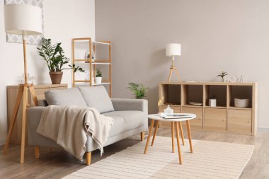 Oturma odasında rahat bir kanepe, çiçekler, raf ünitesi ve kahve masası var.