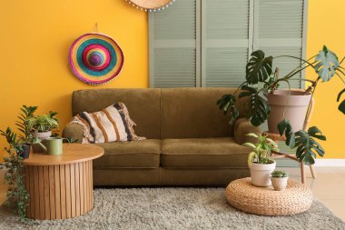 Rahat kanepesi, sehpası ve çiçekleri olan sarı oturma odasının içi.