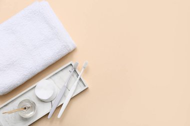 Temiz yumuşak havlular, taş tepsi, pamuk yastıklar ve bej arka planda diş fırçaları ile kompozisyon
