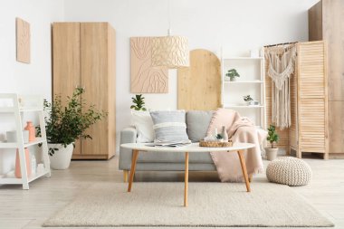 Koltuğu, çiçekleri, raf ünitesi ve sehpası olan şık bir oturma odası.