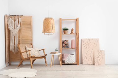 Beyaz oturma odasının içinde rahat koltuğu, sehpası ve raf ünitesi var.