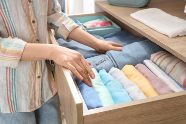 Kadın çekmeceden kot pantolon alıyor. Yakın çekim.