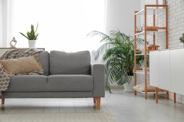 Gri kanepesi ve aydınlık perdesi olan şık bir oturma odası.