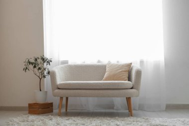 Şık oturma odasının içinde kanepe, çiçek ve ışık perdeleri var.