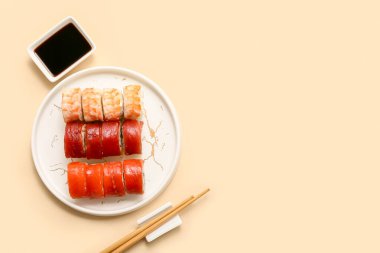 Lezzetli suşi ruloları, soya sosu ve bej arka planda çubuklar.