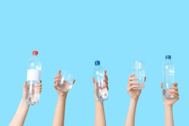 Renkli arka planda şişe ve bardak su taşıyan kadın eller, yakın plan.