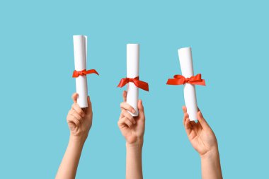 Mavi arka planda diploması olan kadın eller