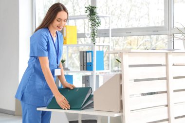 Klinikteki masasında klasörleri olan kadın resepsiyonist.