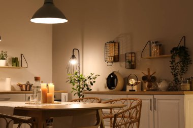 Parlayan lambaları, beyaz tezgahları, masası ve akşam sandalyeleri olan modern mutfağın içinde.