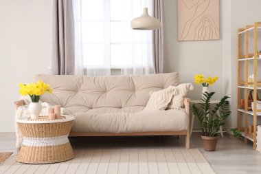 Rahat kanepesi, sehpası ve narsisli çiçekleri olan şık bir oturma odası.