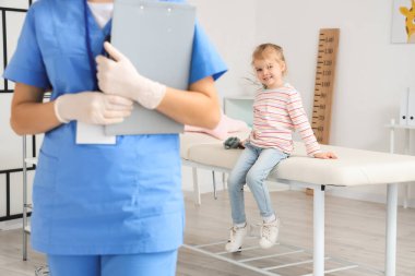 Pediyatri kliniğindeki kanepede oturan tatlı küçük kız.
