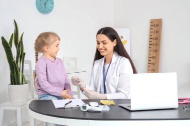 Dil bastırıcısı olan kadın bir çocuk doktoru ve klinikteki küçük bir kız.