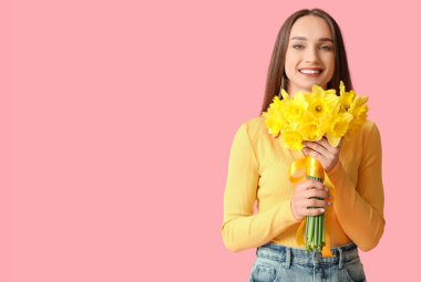 Beautiful young happy woman with bouquet of beautiful narcissus on pink background