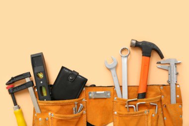 Bej arka planda farklı inşaat araçları ve cüzdanı olan kemer