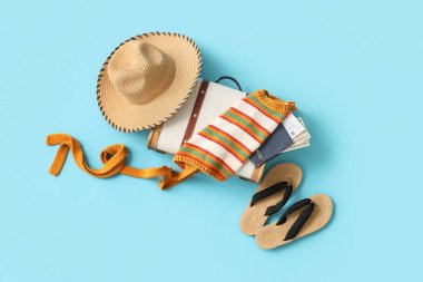 Hasır şapkalı bavul, parmak arası terlik ve mavi arka planda pasaport. Seyahat kavramı