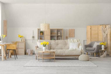 Interior of stylish living room with sofa, coffee table and vase of narcissus flowers