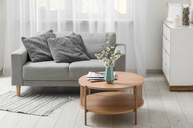 Şık oturma odasındaki masanın üzerinde çiçek açan dalları olan mavi vazo.