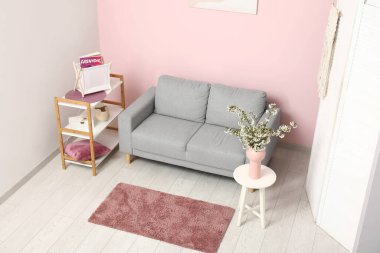 Çiçek açan güzel dalları olan bir vazo ve evdeki kanepe.