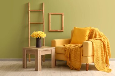 Ekoseli rahat koltuk ve oturma odasında nergis çiçekleri olan kahve masası.