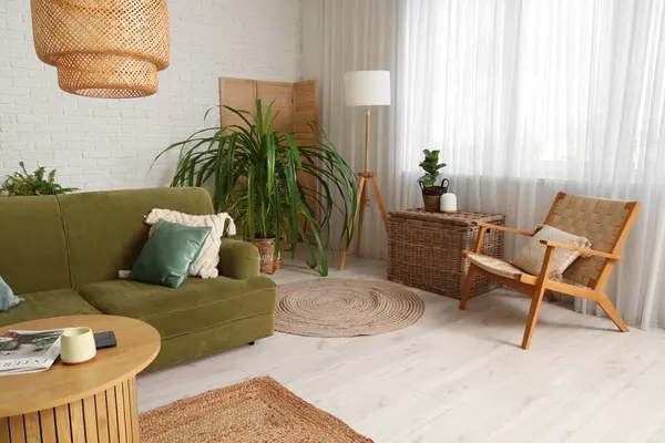 Beyaz oturma odasının içinde yeşil kanepe, lamba ve kahve masası var.