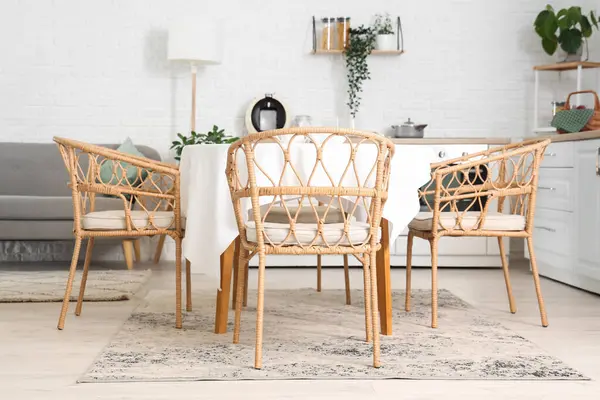 Mutfağın içinde beyaz tezgahlar, gri kanepe ve yemek masası var.