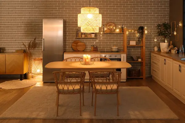 Parlayan lambaları, beyaz tezgahları, buzdolabı, masa ve sandalyeleri olan şık bir mutfak.