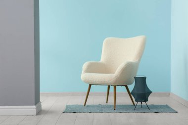 Mavi duvarın yanında beyaz koltuk ve lamba
