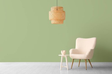 Yeşil duvarın yanında kahve masası ve lamba olan beyaz koltuk.