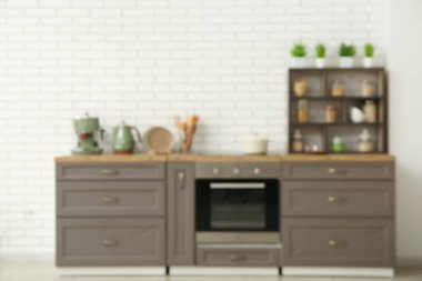 Fırın, kahverengi tezgah ve raf ünitesiyle mutfağın şık iç mekanı bulanık görünüyor.