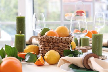 Oturma odasında turunçgil meyveleri, yanan mumlar ve bardaklarla dolu güzel bir masa.